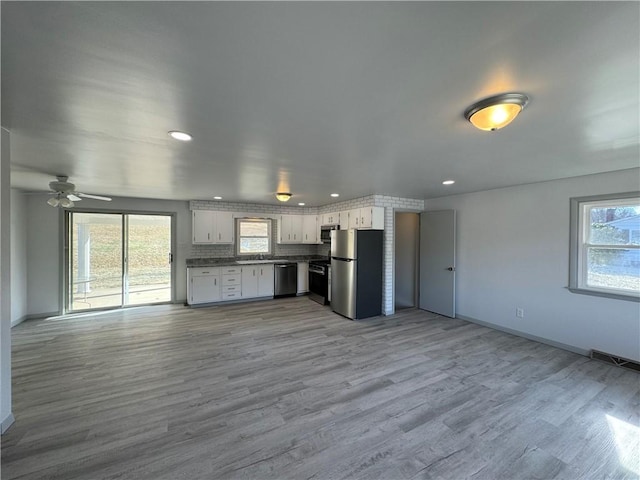 kitchen featuring appliances with stainless steel finishes, a healthy amount of sunlight, white cabinets, and light hardwood / wood-style flooring