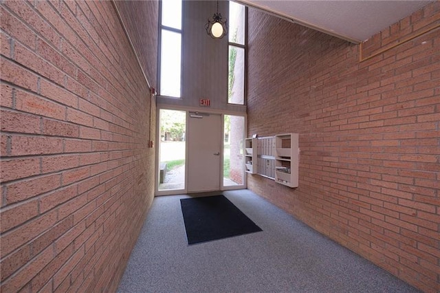 interior space with brick wall, carpet, and a high ceiling