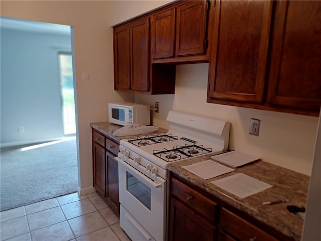 kitchen featuring light carpet, white appliances, and stone counters