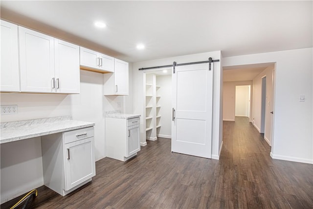 kitchen featuring white cabinetry, dark hardwood / wood-style floors, a barn door, and light stone counters