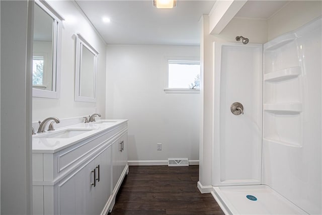 bathroom with hardwood / wood-style flooring, vanity, and walk in shower