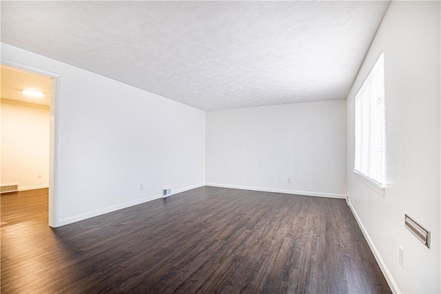 unfurnished room with dark hardwood / wood-style flooring and a textured ceiling