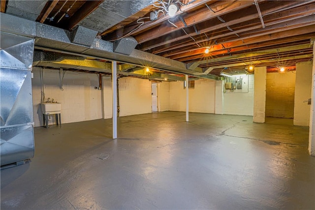 basement featuring electric panel, sink, and heating unit