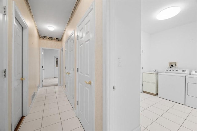 corridor with light tile patterned floors and independent washer and dryer