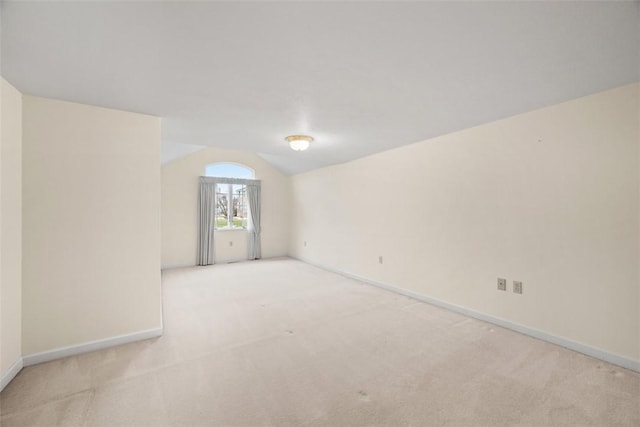 spare room featuring lofted ceiling and light colored carpet