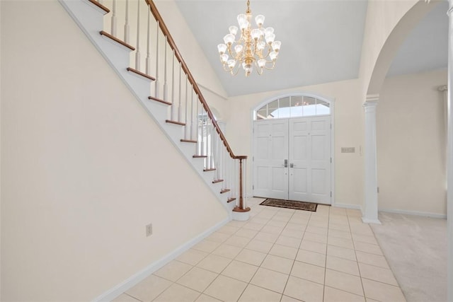 tiled entryway featuring decorative columns, a notable chandelier, and high vaulted ceiling