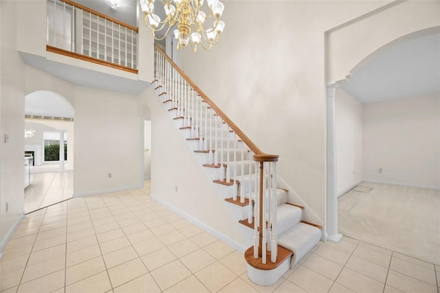 staircase with tile patterned floors, decorative columns, and a high ceiling