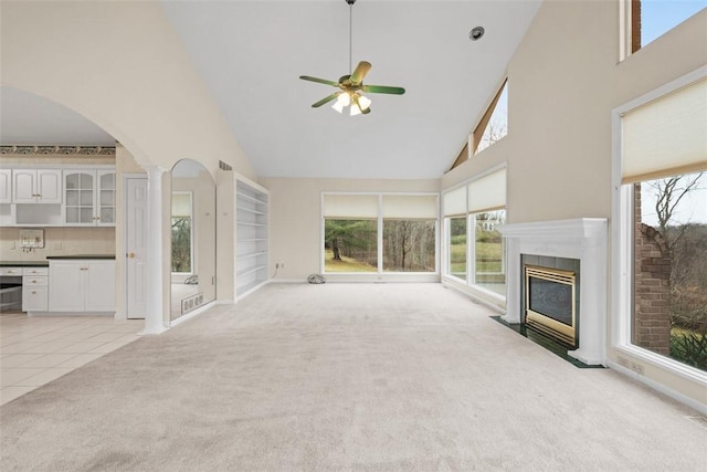 unfurnished living room with a towering ceiling, light colored carpet, and a healthy amount of sunlight