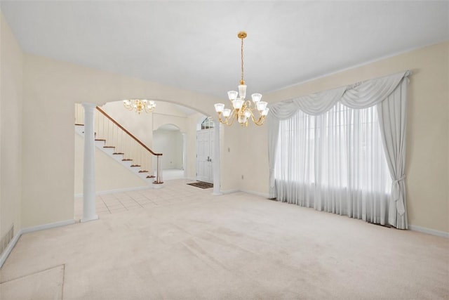 carpeted empty room with decorative columns and a notable chandelier