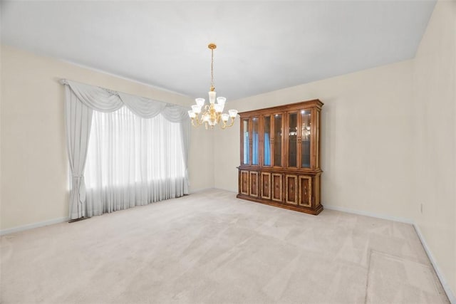 unfurnished room featuring a chandelier and light carpet