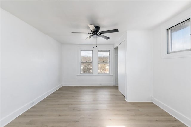 empty room with a ceiling fan, baseboards, and light wood-style floors