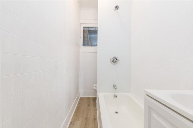 bathroom featuring vanity, toilet, baseboards, wood finished floors, and  shower combination