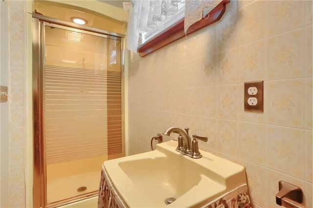 bathroom featuring sink, a shower with shower door, and tile walls