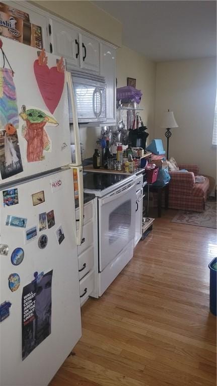 kitchen featuring white appliances, white cabinets, and light hardwood / wood-style floors