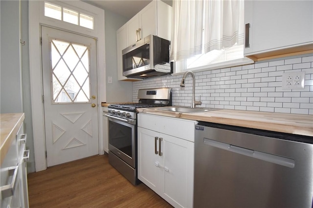 kitchen featuring butcher block countertops, light hardwood / wood-style floors, sink, appliances with stainless steel finishes, and white cabinets