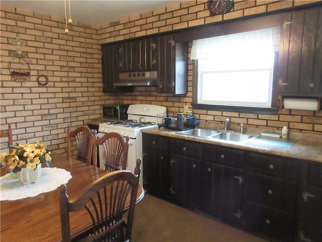 kitchen with sink, white range with gas cooktop, dark brown cabinets, and brick wall