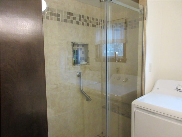 bathroom featuring a shower with shower door and washer / clothes dryer