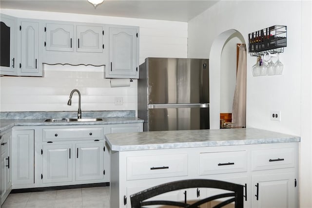216 Karen Dr, Allegheny Twp Wml, PA 15613 - kitchen with arched walkways, a sink, light tile patterned flooring, freestanding refrigerator, and light countertops