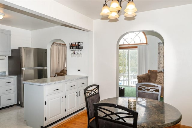 216 Karen Dr, Allegheny Twp Wml, PA 15613 - kitchen with white cabinets, arched walkways, freestanding refrigerator, an inviting chandelier, and hanging light fixtures