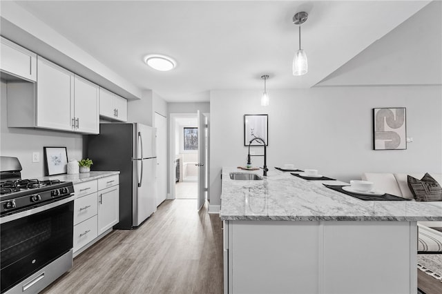 kitchen featuring light stone counters, white cabinetry, decorative light fixtures, sink, and gas range oven