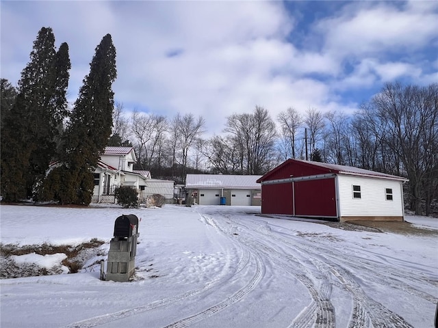 snowy yard featuring a detached garage and an outdoor structure