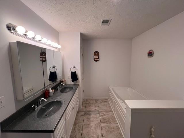 bathroom featuring a textured ceiling, a tub to relax in, and vanity