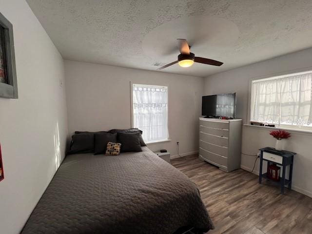 bedroom with a textured ceiling, ceiling fan, and wood-type flooring