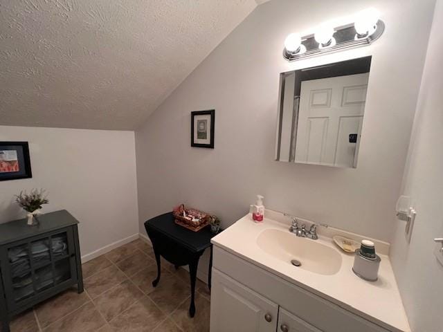 bathroom with tile patterned floors, a textured ceiling, vaulted ceiling, and vanity