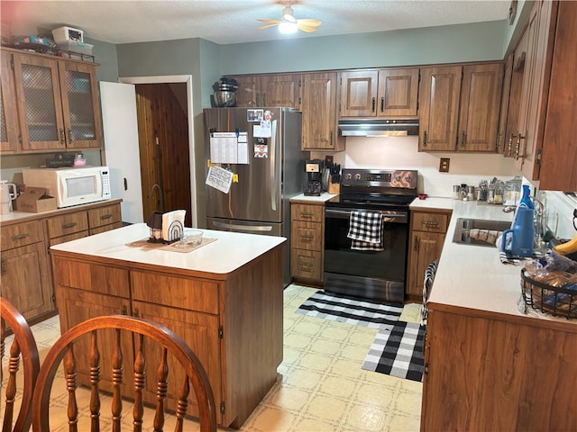 kitchen with range with electric stovetop, ceiling fan, stainless steel fridge, a kitchen island, and sink