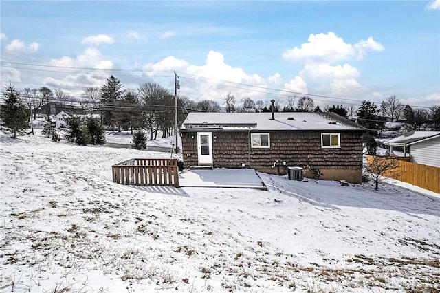 snow covered back of property featuring central AC