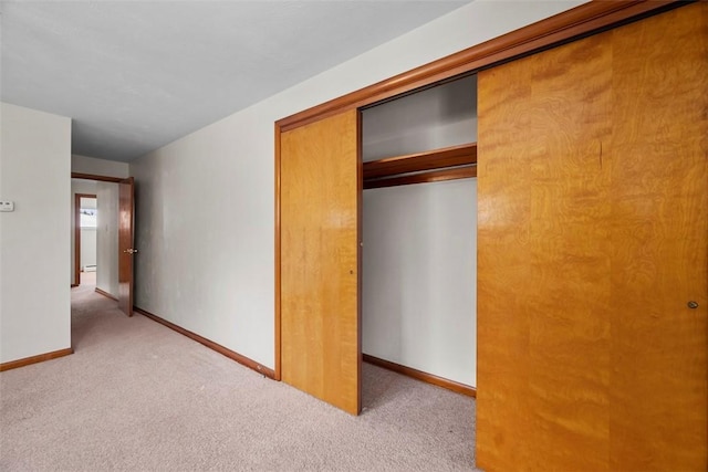 unfurnished bedroom featuring a closet and light colored carpet