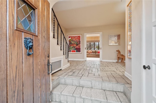 entrance foyer with stairway, brick floor, and baseboards