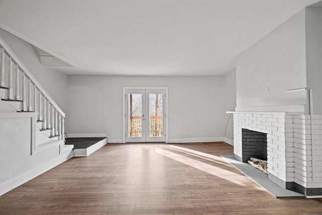 unfurnished living room featuring a brick fireplace, french doors, and wood-type flooring