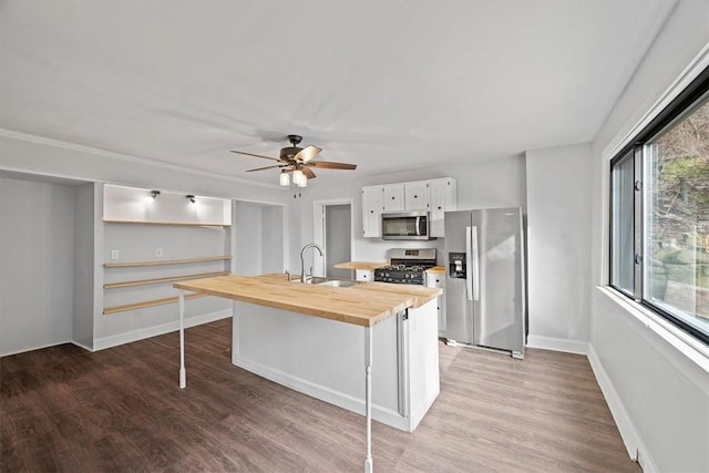 kitchen with a wealth of natural light, sink, wood counters, appliances with stainless steel finishes, and white cabinets