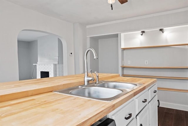 kitchen with butcher block countertops, white cabinets, ceiling fan, dark hardwood / wood-style flooring, and sink