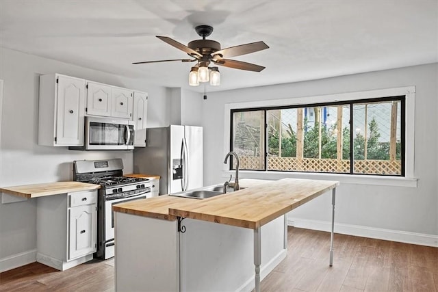 kitchen featuring wooden counters, white cabinetry, stainless steel appliances, and sink