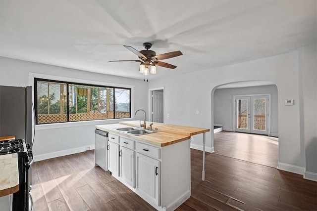 kitchen with a kitchen island with sink, stainless steel appliances, butcher block counters, sink, and white cabinets