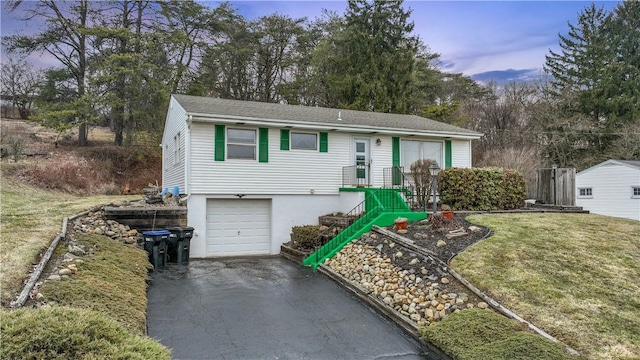 ranch-style house with a garage, driveway, and a lawn