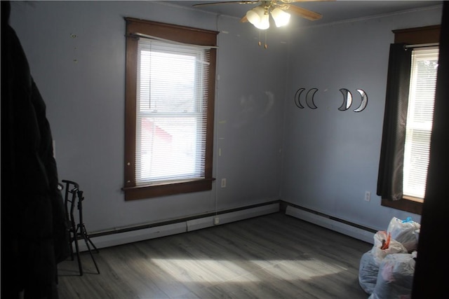 spare room with hardwood / wood-style flooring, ceiling fan, and a baseboard heating unit