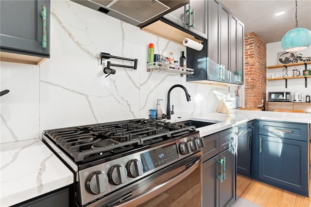 kitchen with light hardwood / wood-style flooring, gas stove, sink, light stone countertops, and decorative backsplash