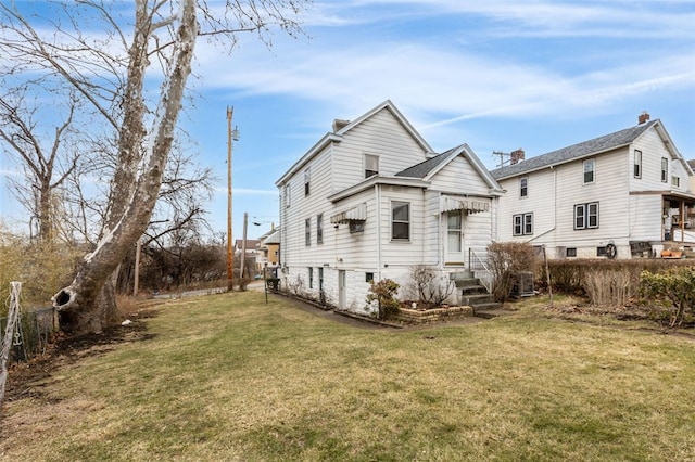 rear view of house featuring cooling unit and a yard