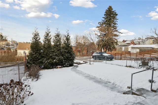 snowy yard with a residential view and fence