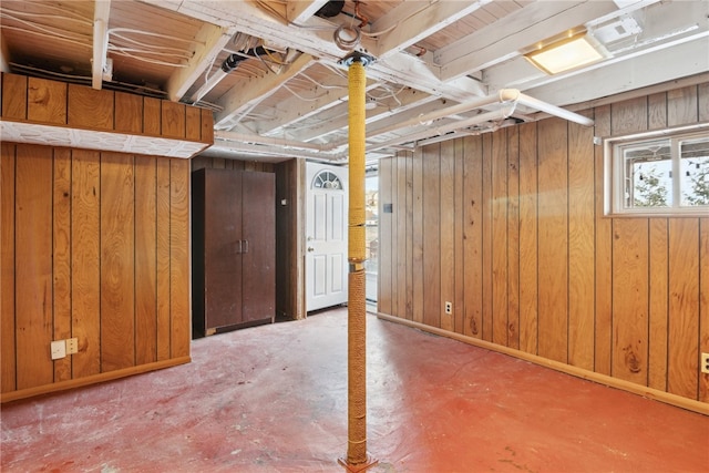 basement with baseboards and wooden walls