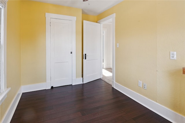 unfurnished bedroom with dark wood finished floors and baseboards