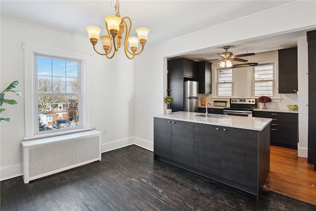 kitchen with radiator heating unit, appliances with stainless steel finishes, dark wood-type flooring, decorative light fixtures, and a sink