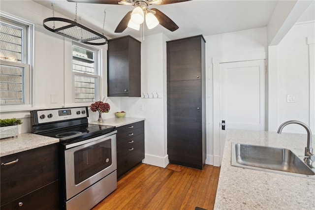 kitchen with dark brown cabinetry, light countertops, a sink, and stainless steel electric range