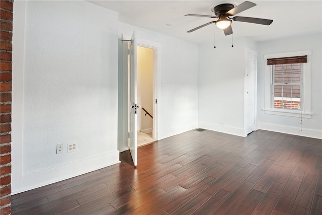 unfurnished room featuring ceiling fan, baseboards, and dark wood finished floors