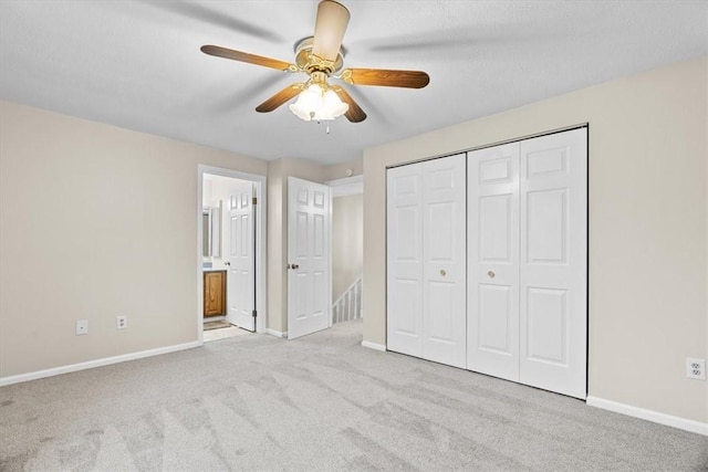 unfurnished bedroom featuring light carpet, ensuite bathroom, a closet, and ceiling fan