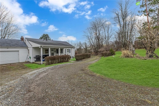 ranch-style house featuring covered porch, a front yard, and a garage