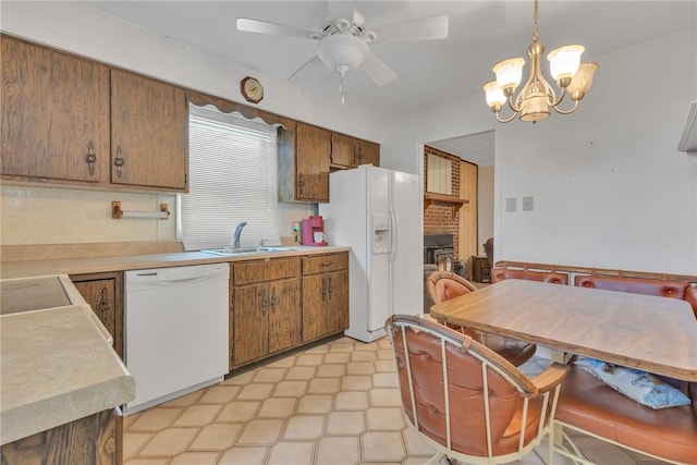 kitchen featuring a fireplace, decorative light fixtures, sink, white appliances, and ceiling fan with notable chandelier